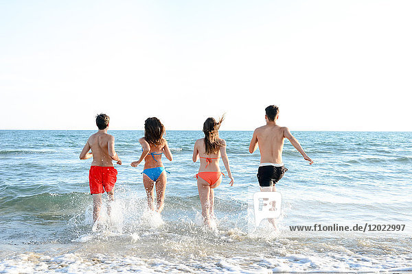 Frankreich  4 junge Leute laufen von hinten ins Meer  um zu baden.