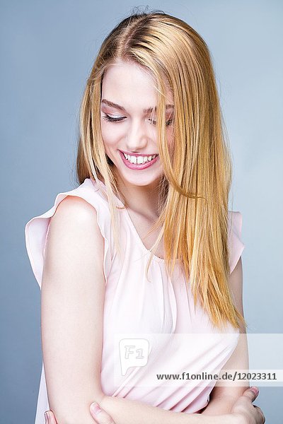 Porträt einer lächelnden jungen Frau mit gesenktem Kopf
