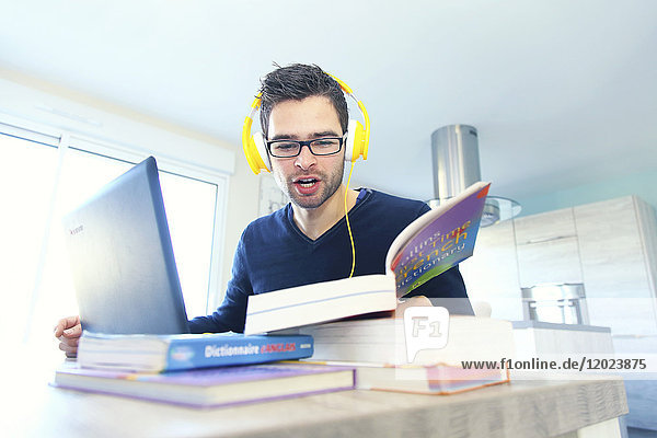Junger Mann lernt zu Hause eine neue Sprache am Computer.