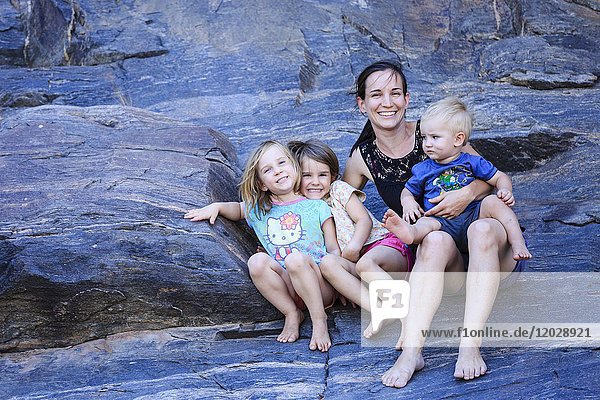 Mutter und drei Kleinkinder sitzen auf Felsen  Damaraland  Kunene-Region  Namibia  Afrika