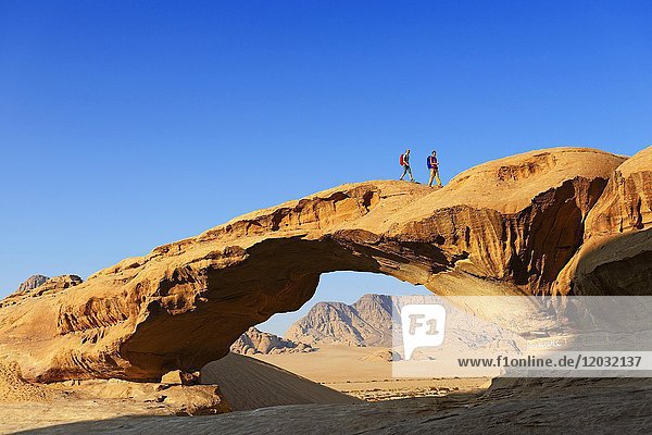 Couple hiking at Rock-Arch named Al Kharza  Wadi Rum  Jordan  Asia