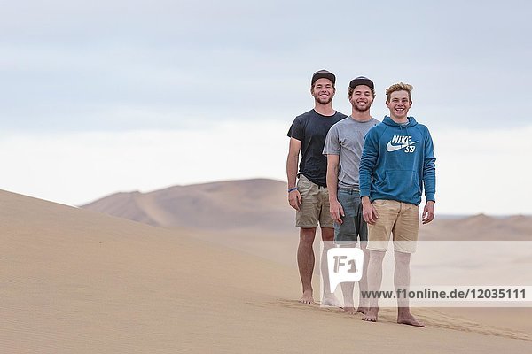 Drei junge Männer auf einer Sanddüne  Namib-Wüste  Namibia  Afrika