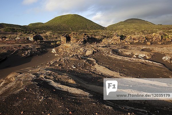 Überreste von Häusern ragen aus der Lava-Asche hinter den Vulkanen Cabeco do Carito und Cabeco Verde  Capelo  Insel Faial  Azoren  Portugal.