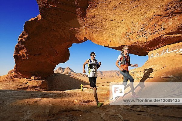 Paar joggt am Rock-Arch mit dem Namen Al Kharza  Wadi Rum  Jordanien  Asien