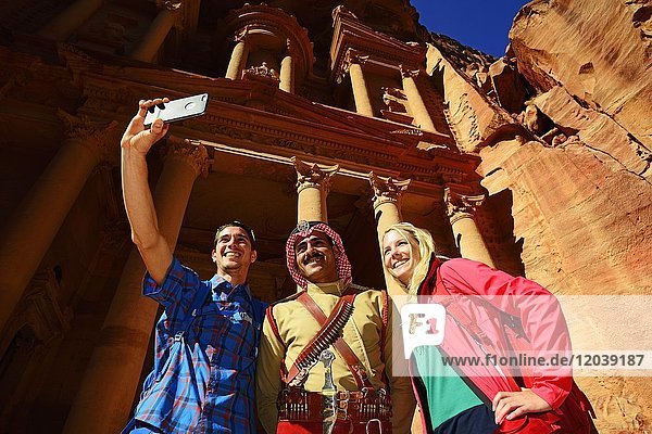 Tourists take a shot with a Bedouin Policeman at Khazne al Firaun  Al Khazneh treasury building  Petra  Wadi Musa  Jordan  Asia