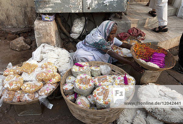 Frau in weißem Sari  die auf der Straße in der Nähe des hinduistischen Jagannath-Tempels  der Lord Vishnu geweiht ist  Puja-Opfer aus Körben verkauft  Puri  Odisha  Indien  Asien