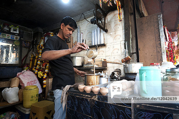 Chai Wallah  der indischen Chai in traditionelle handgefertigte Terrakotta-Tassen gießt  in einem Chai-Stand vor dem Kali-Tempel  Kalkutta  Westbengalen  Indien  Asien