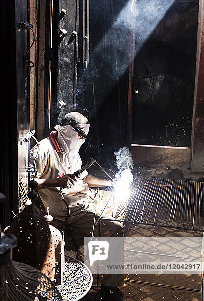 Worker in Blacksmiths Souk welding metal Marrakech Morocco North Africa Africa