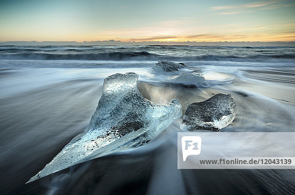 Angeschwemmte Gletschereisstücke am schwarzen Vulkansandstrand bei Sonnenaufgang  in der Nähe der Gletscherlagune Jokulsarlon  Südisland  Polarregionen