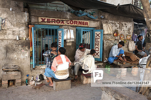 Barbers cutting hair and shaving men  and tobacco wallah  in street stalls outside Xerox shop in Dalhousie Square area of Kolkata (Calcutta)  West Bengal  India  Asia