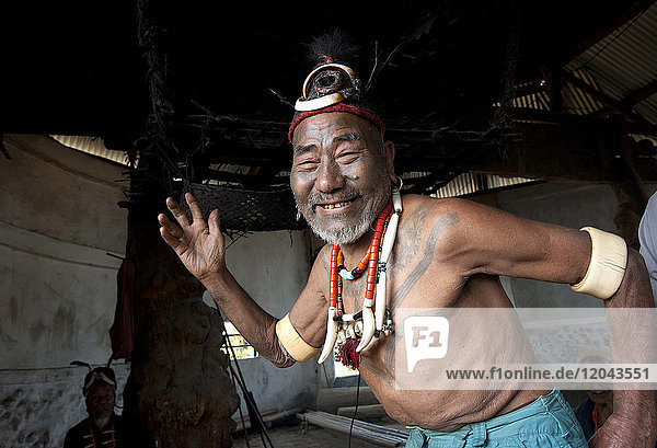 Lächelnder Naga-Mann  Kopfjäger  Wokshing Pensha  beim spielerischen Stammestanz  mit Naga-Halsketten und Elefantenstoßzahn-Armbändern  Nagaland  Indien  Asien