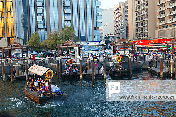 A water taxi carrying passengers arrives at a busy dock  Dubai Creek  Dubai  United Arab Emirates  Middle East