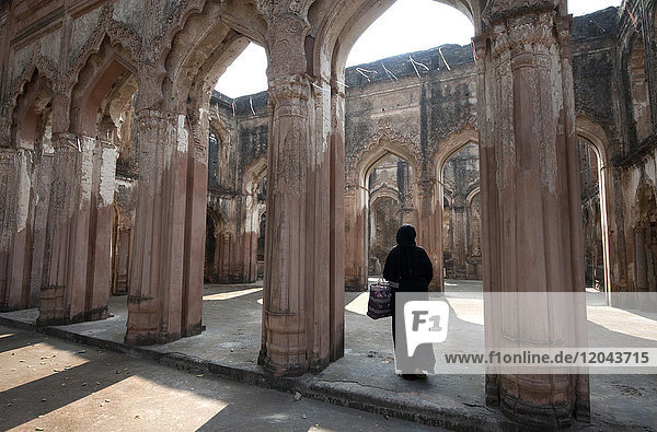 Muslim woman entering the semi-derelict 18th century Imambara and Mosque  Lucknow Residency  Uttar Pradesh  India  Asia