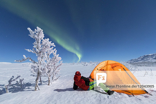 Wanderer vor einem Zelt betrachtet die Nordlichter (Aurora Borealis)  Abisko  Gemeinde Kiruna  Landkreis Norrbotten  Lappland  Schweden  Skandinavien  Europa