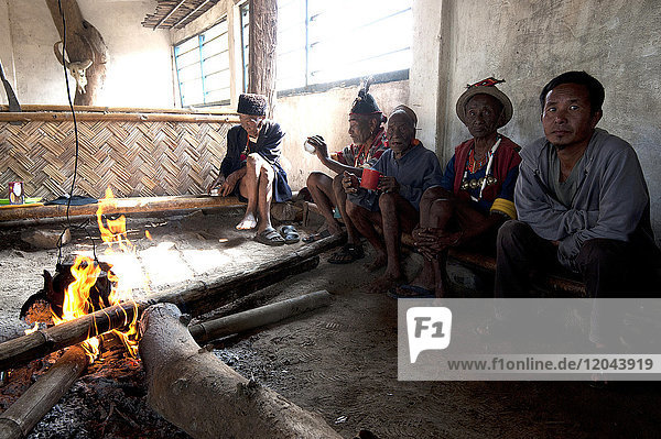 Naga-Männer sitzen plaudernd am Feuer im Dorf Muting (Versammlungsraum)  Nagaland  Indien  Asien