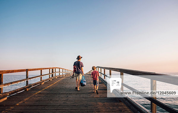 Rear view of father and son walking on pier Goleta California United States North America
