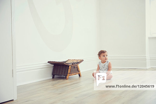 Kleinkind sitzt auf dem Boden im kahlen Zimmer