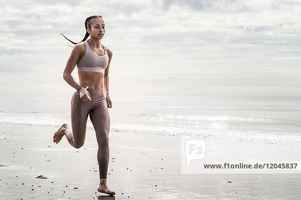 Young woman running along beach