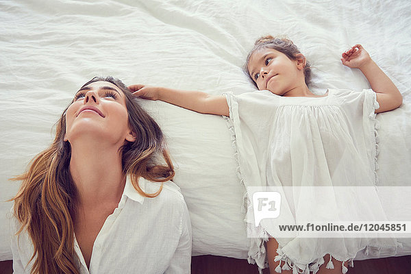 Mother and daughter relaxing in bedroom  leaning against bed