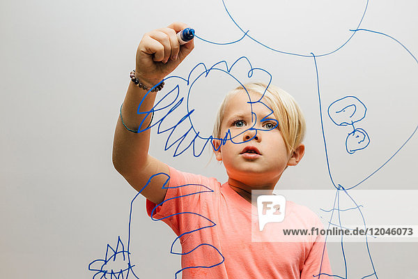 Boy drawing with marker pen onto glass wall