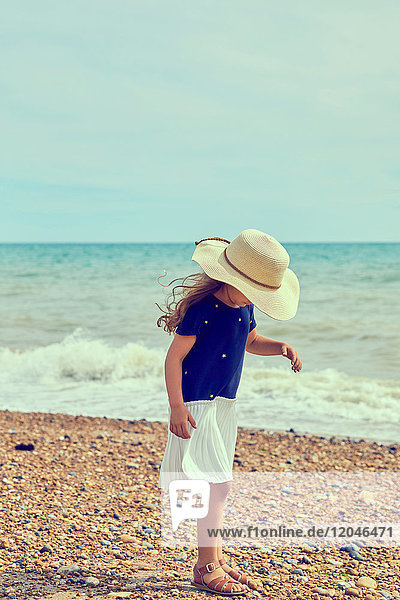 Young girl  standing on beach  looking for shells