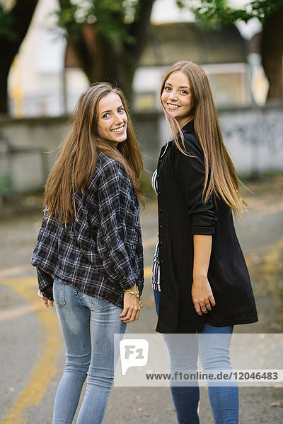 Porträt von zwei jungen Freundinnen  die sich im Park über die Schulter schauen