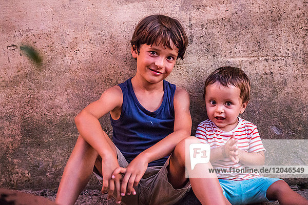 Porträt eines Jungen und eines kleinen Bruders  die an der Wand sitzen