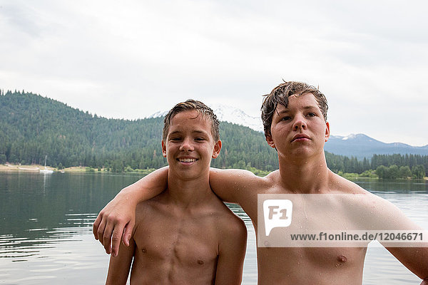 Portrait of two teenage brothers beside water