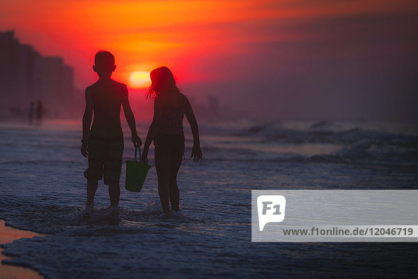 Geschwister paddeln im Meer bei Sonnenuntergang  North Myrtle Beach  South Carolina  Vereinigte Staaten