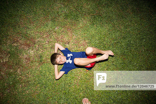 Junge auf dem Rücken auf Gras liegend  Blick von oben