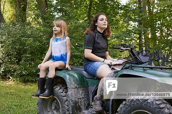 Two girls  sitting on quad bike