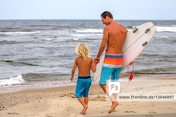 Erwachsener männlicher Surfer und Sohn auf dem Weg zum Meer  Asbury Park  New Jersey  USA