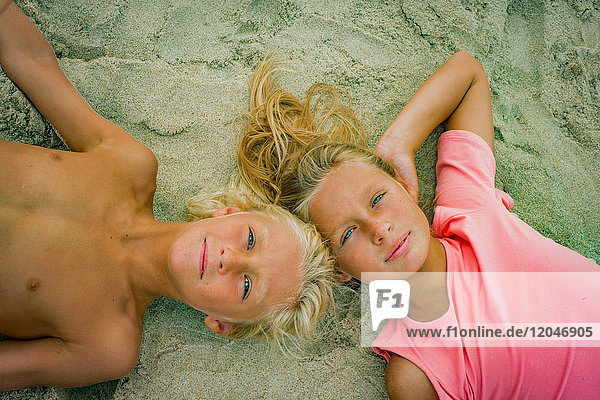 Portrait eines blonden Bruders und einer blonden Schwester am Strand liegend