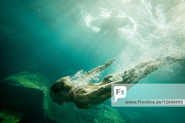 Junger Mann schwimmt unter Wasser