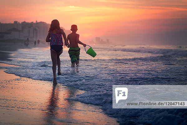 Siblings paddling in sea at sunset  North Myrtle Beach  South Carolina  United States