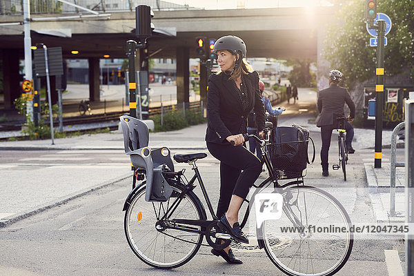 Businesswoman with bicycle on street in city