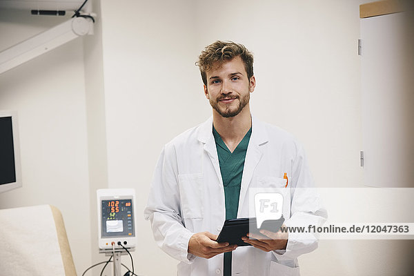 Portrait eines selbstbewussten männlichen Arztes mit digitaler Tablette im Krankenhaus