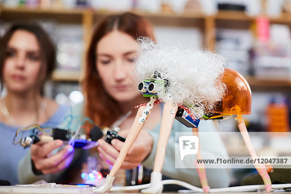 Young female inventors making robot model at workshop