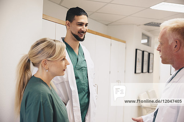 Reife Ärztin im Gespräch mit Kollegen im Krankenhauskorridor