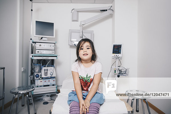 Portrait of girl sitting on bed at hospital