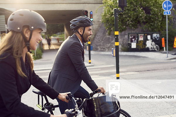 Side view of smiling business coworkers cycling in city