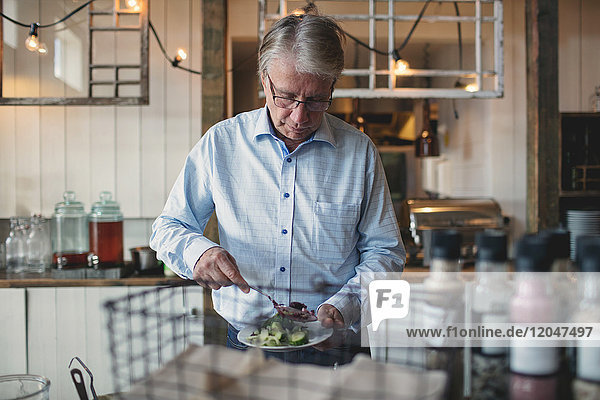 Senior Mann beim Essen im Teller an der Buffettheke