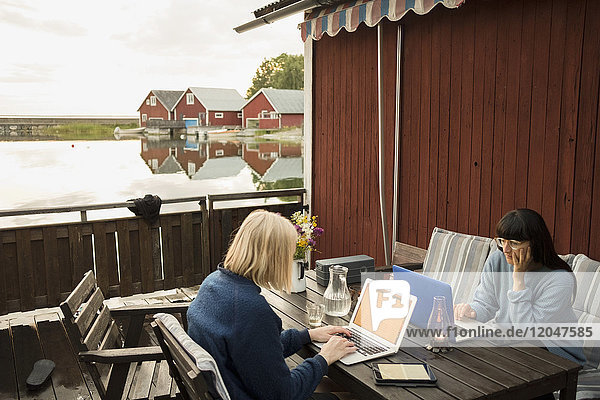 Frauen mit Laptop am Tisch in der Ferienvilla am See
