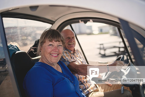 Porträt einer lächelnden älteren Frau und eines Mannes  die an einem sonnigen Tag eine Autofahrt genießen.
