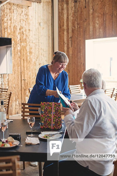 Seniorenfrau schenkt Freundin am Tisch im Restaurant während der Mittagsfeier