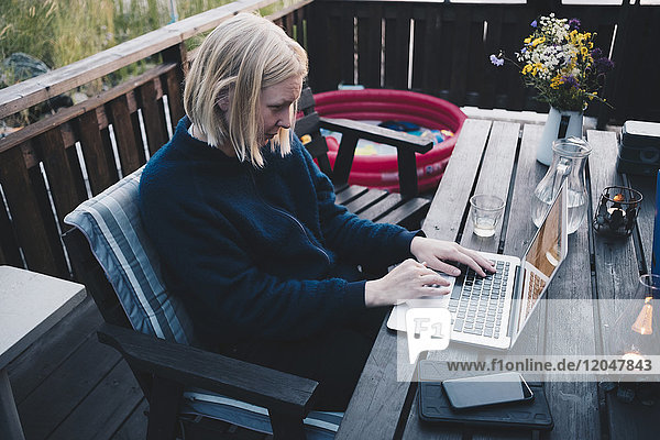Woman using laptop on wooden table at holiday villa