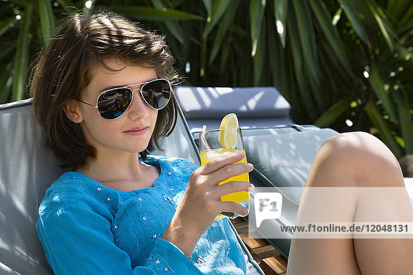Junges Mädchen entspannt sich am Pool mit einem Getränk
