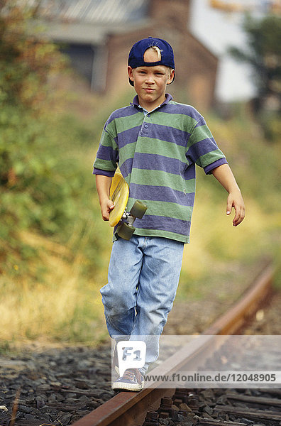 Junge mit Skateboard entlang der Bahngleise