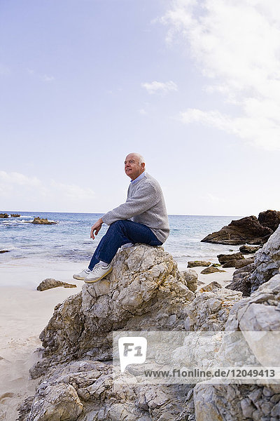 Man Sitting on Rocks on the Beach