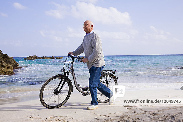 Mann mit Fahrrad am Strand